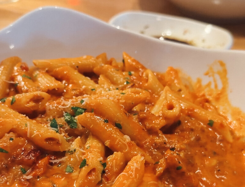 A bowl of creamy penne pasta topped with parmesan and herbs at il Cigno Italiano in Swansboro